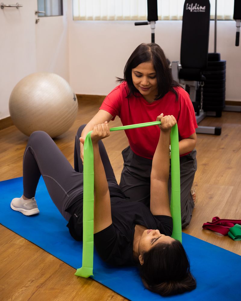Dr. Rajani Patil guiding a patient through a resistance-band exercise at the Orthosports clinic